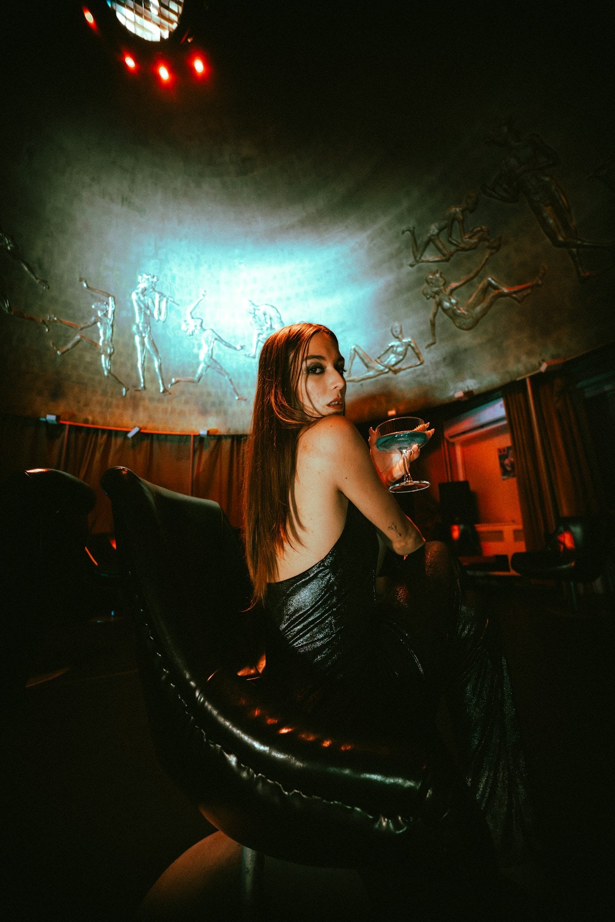 A guest holding a cocktail in a dimly lit venue.