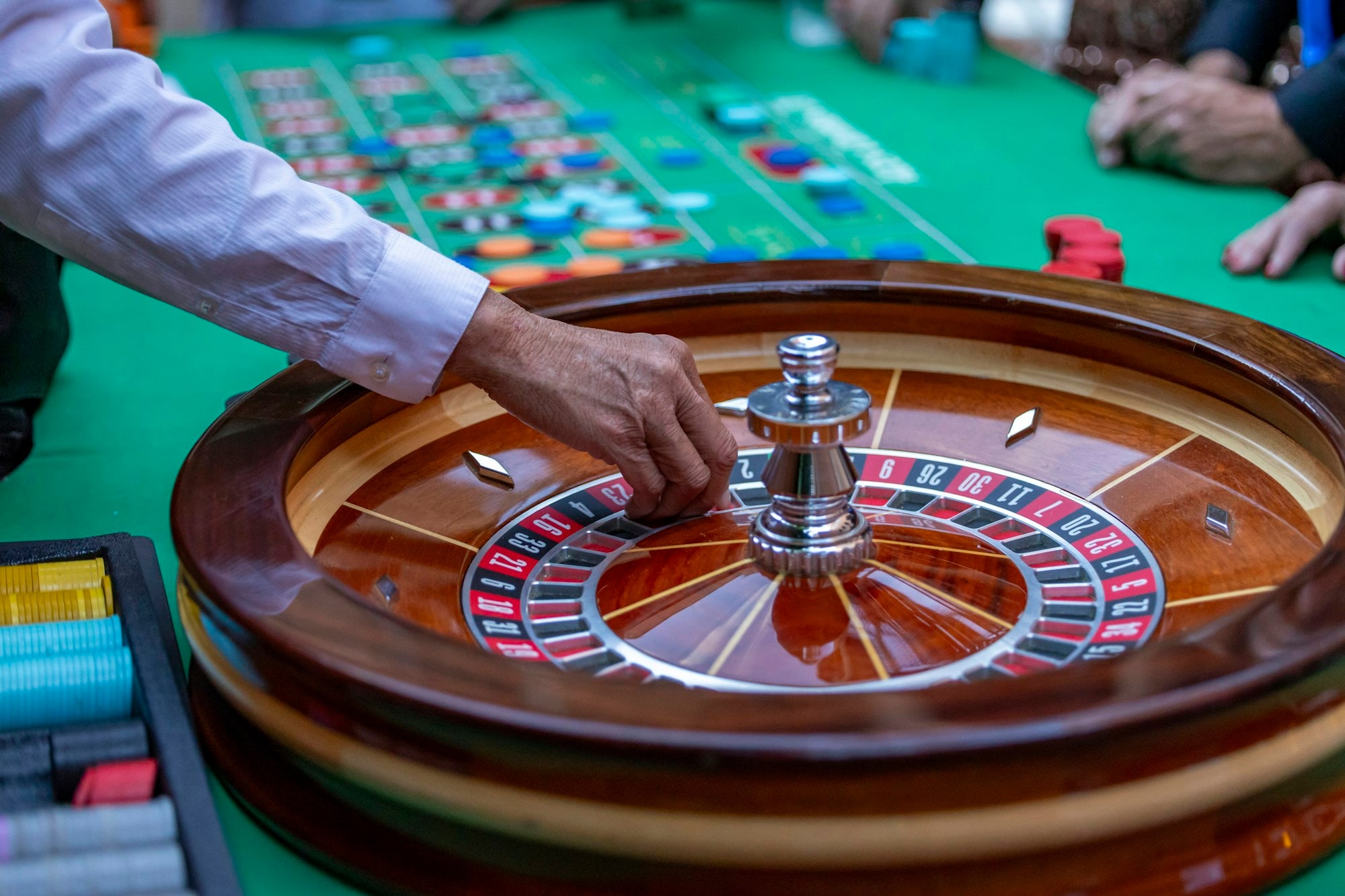 A croupier's hand setting the ball into a polished roulette wheel.